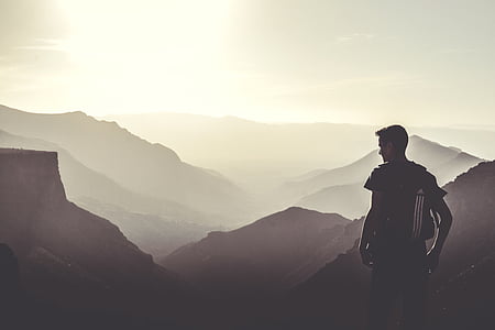 silhouette photo of man standing beside mountains thumbnail