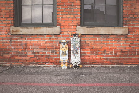 Two White and Brown Longboard Leaning on Brown Bricks Wall thumbnail