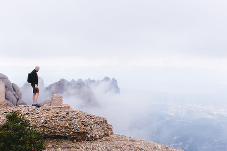 man in black shorts standing on brown cliff thumbnail