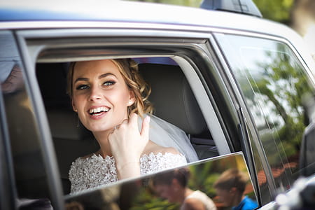 smiling woman wearing wedding dress sitting on car seat during daytime thumbnail