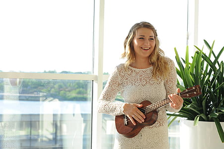Woman Wearing White Floral Dress Playing Ukulele thumbnail