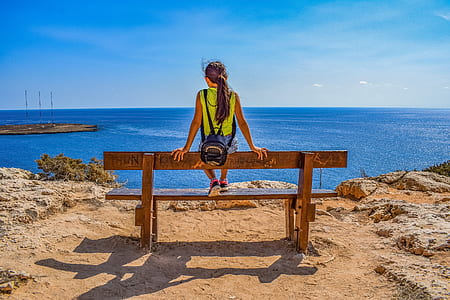 woman sitting on bench near body of water thumbnail