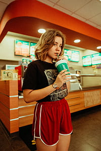 shallow focus photography of woman drinking in white and green plastic tumbler thumbnail