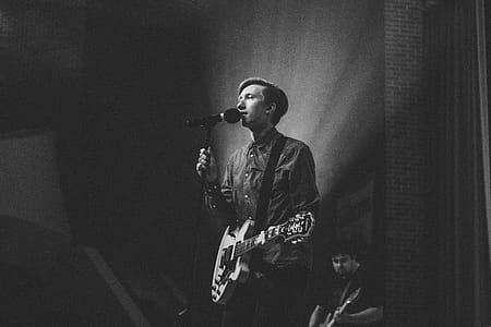 Grayscale Photography of Person Near on Pedestal Microphone thumbnail