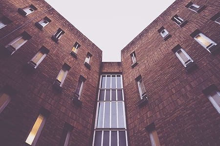 low angle photography of brown concrete building under white clouds thumbnail