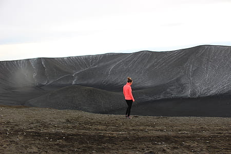 woman wearing red sweater standing near gray mountain thumbnail