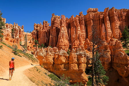 woman walking on brown ground in front of brown rock formation during daytime thumbnail