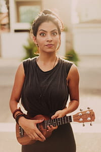 Woman Holding Brown Ukulele String Instrument thumbnail