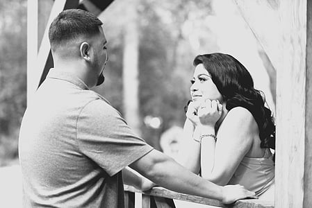 grayscale photo of woman leaning on terrace looking through man standing in front her thumbnail