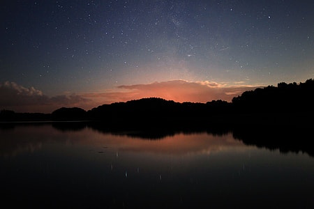 landscape photography of body of water and green trees during sunset thumbnail