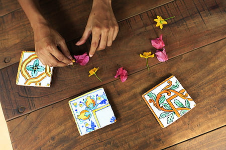 person touching yellow and pink flowers on top of table thumbnail