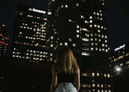 woman looking into high rise building during nighttime thumbnail