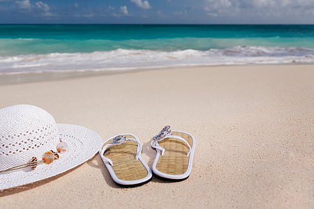 pair of brown flip flops beside white sunhat thumbnail