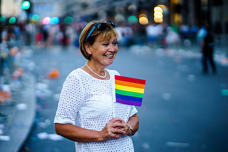 woman holding rainbow flaglet on road during daytime thumbnail