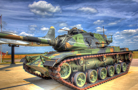green, black, and orange battle tank beside fighter plane thumbnail