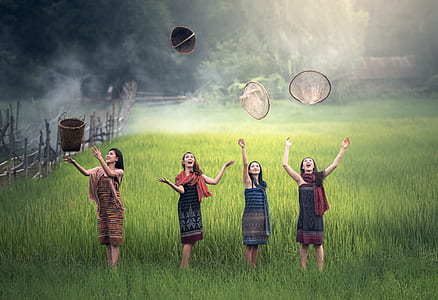 four women on rice field throwing baskets at daytime thumbnail