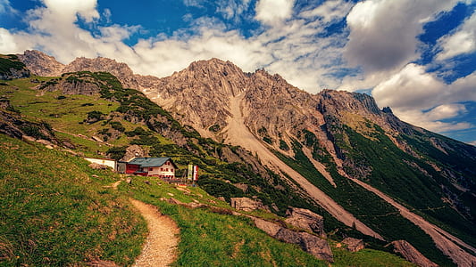 brown house on mountain under cloudy sky thumbnail
