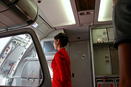 woman in red jacket looking outside the plane thumbnail
