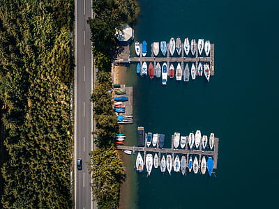 aerial photography of lake dock with boats and car running on road near trees at daytime thumbnail