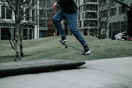 person doing ollie skateboard trick over gray concrete ledge at daytime thumbnail