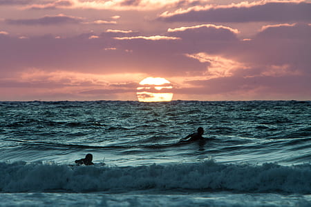 silhouette of person surfing under cloudy sky thumbnail
