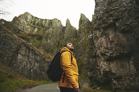 man wearing yellow hooded jacket and backpack thumbnail