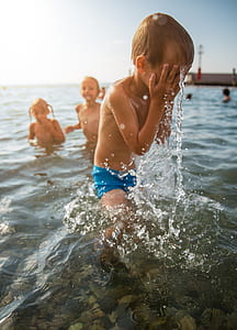 boy wearing blue swimming trunks wiping his wet face thumbnail