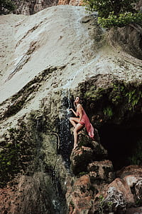 woman sitting on stone holding waterfalls pouring thumbnail