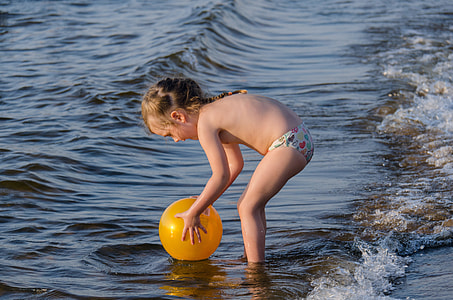 girl standing on seashore holding ball thumbnail