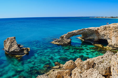brown rock formation surrounded by body of water during daytime thumbnail