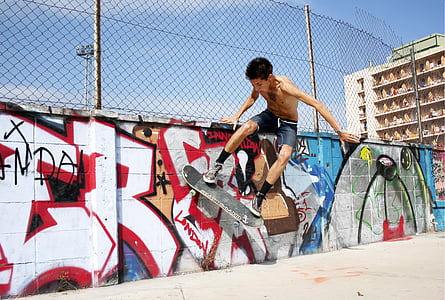 man riding skateboard doing tricks beside fence thumbnail
