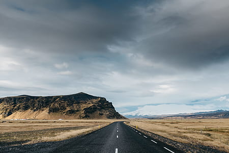 grey concrete road between brown land near brown mountain during daytime thumbnail