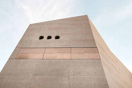 low angle photo of brown concrete structure under cloudy sky thumbnail