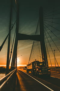 red MACK trailer truck running steel bridge during golden hour thumbnail