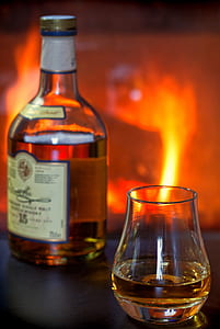 bottle beside brandy glass filled with liquor thumbnail