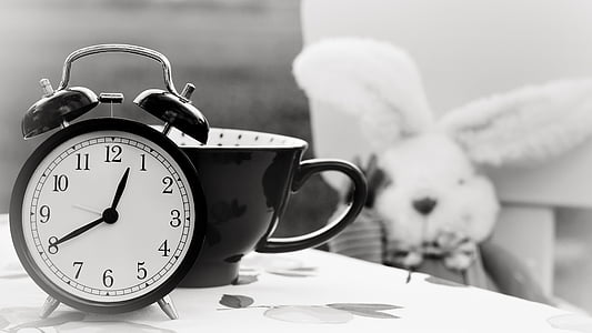 black and white alarm clock beside mug thumbnail