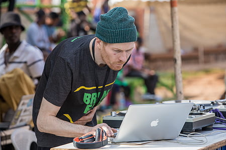 Dj holding MacBook silver besde DJ controller thumbnail
