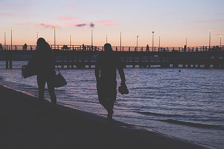 silhouette of two people walking on seashore thumbnail