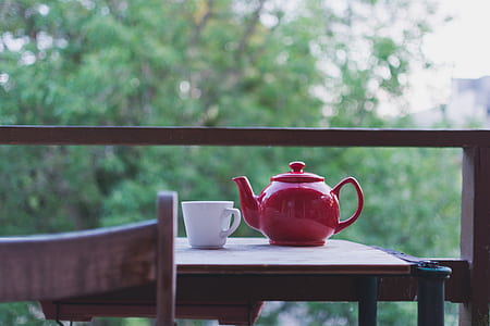 selective focus photography of red teapot and white ceramic teacup on table near on balcony thumbnail