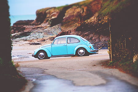 teal Volkswagen Beetle parked on seashore at daytime thumbnail
