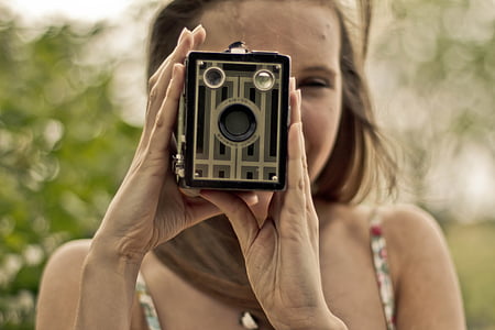 woman wearing white spaghetti strap top holding gray land camera thumbnail