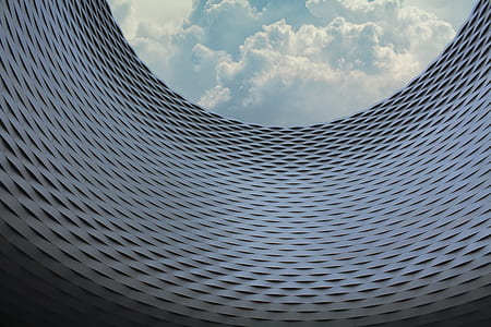 worm's-eye view of grey wall under cloudy sky thumbnail