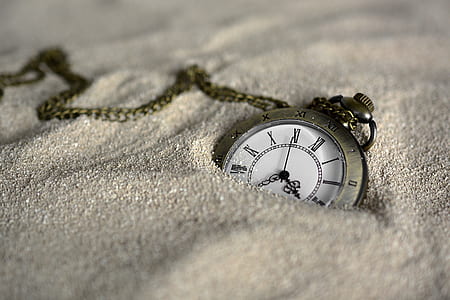 shallow focus photography of pocket watch on white sands thumbnail