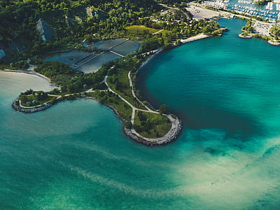 aerial view of body of water surrounding land with trees thumbnail
