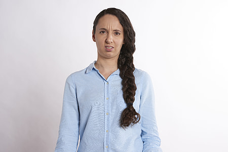woman in blue dress shirt standing near white painted wall thumbnail