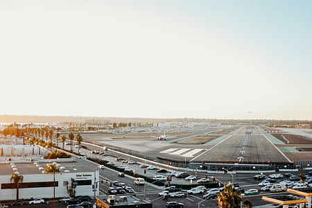 aerial photo of vehicles on road beside airport runway thumbnail