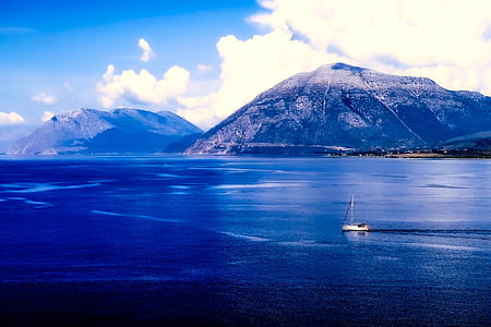 white sailboat on body of water near mountains thumbnail