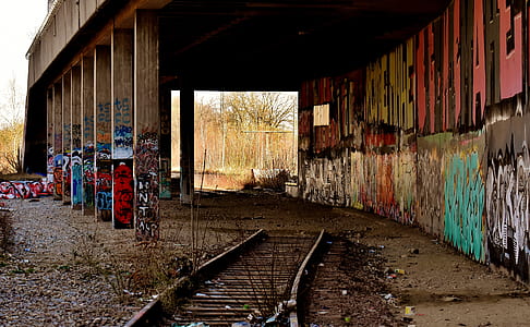 gray train railway between wall with graffiti thumbnail