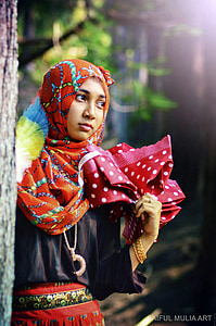 fashion photography of woman wearing multicolored hijab and black batwing top beside tree thumbnail