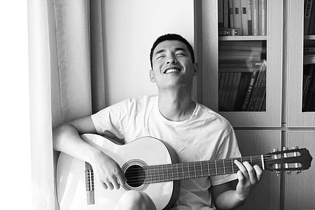 grayscale photo of man smiling while playing classical guitar thumbnail